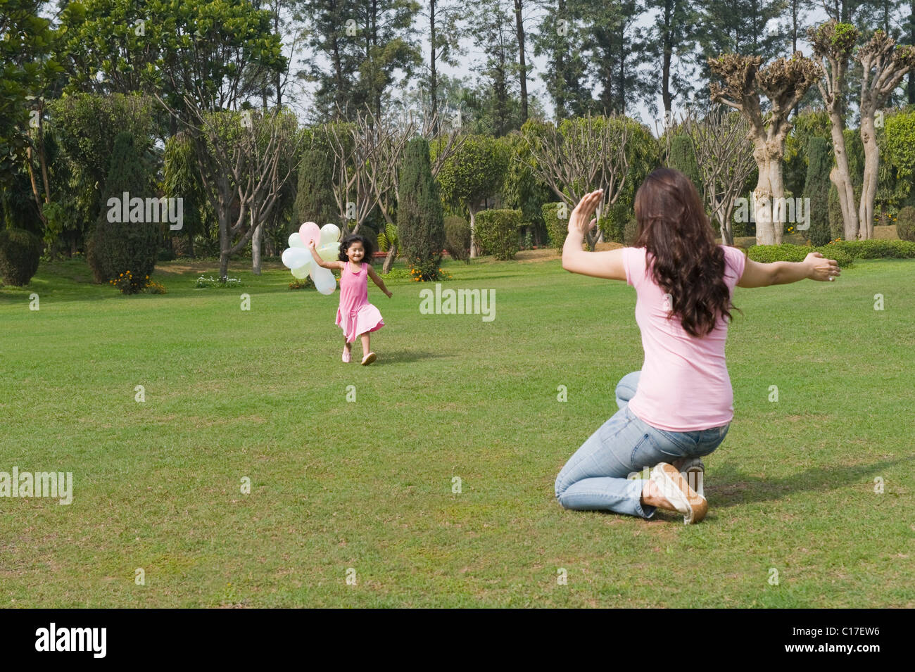 Girl running with balloons towards her mother in a park Stock Photo - Alamy