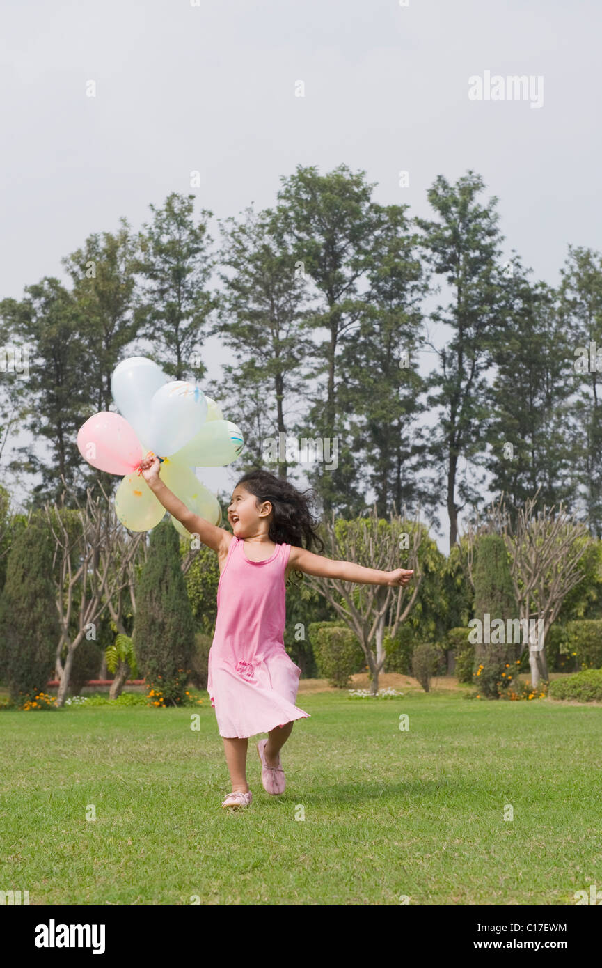 Girl running with balloons in a park Stock Photo - Alamy