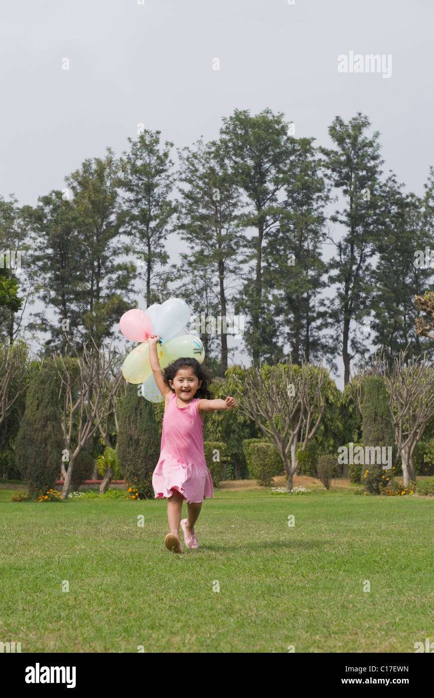 Girl running with balloons in a park Stock Photo - Alamy