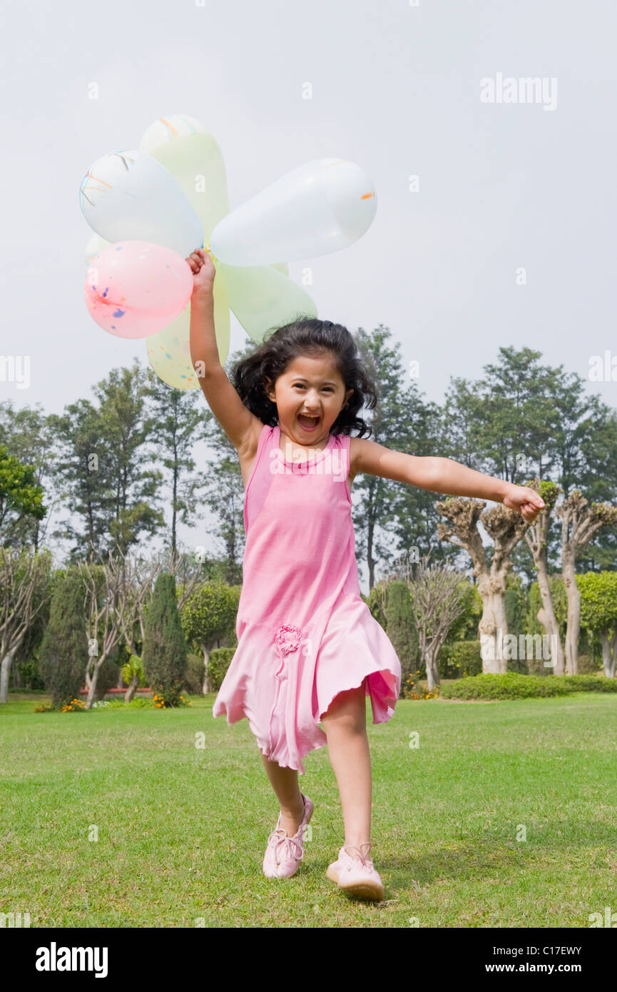 Girl running with balloons in a park Stock Photo - Alamy