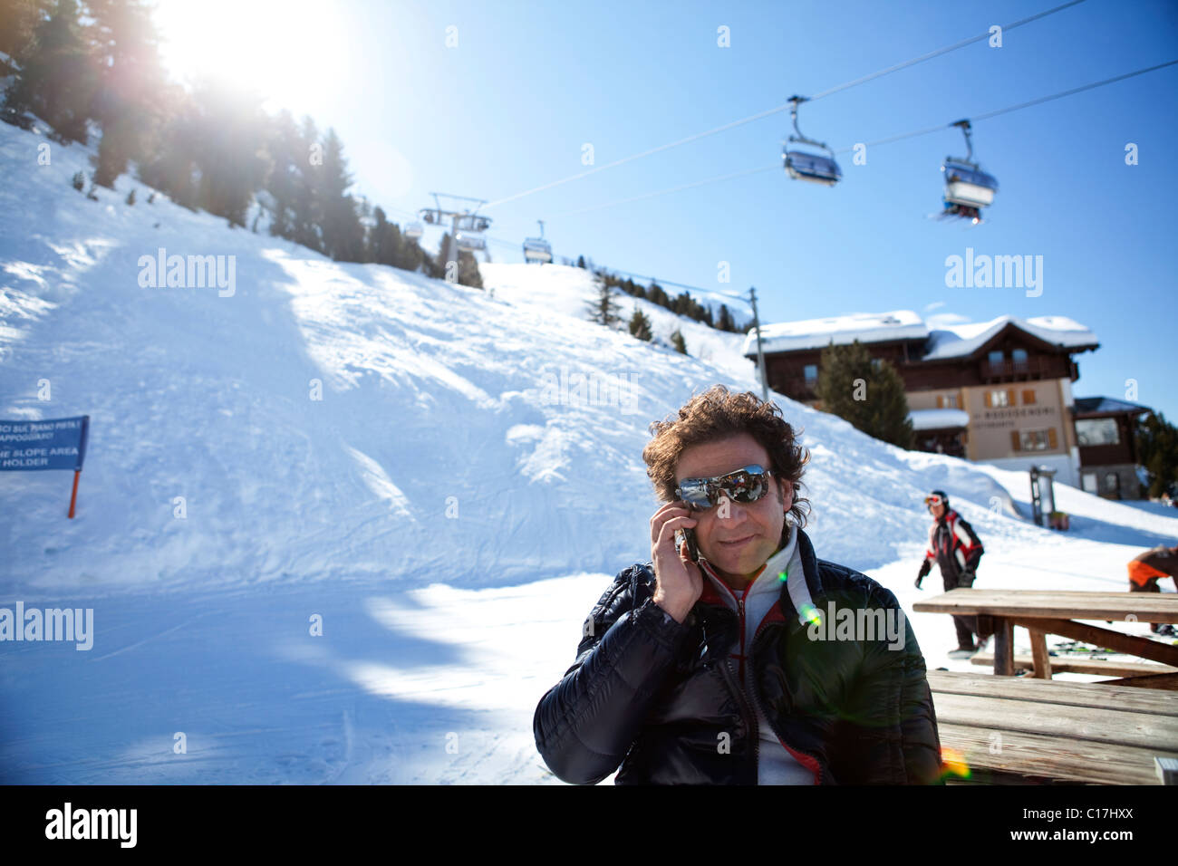 Man with sunglasses on the iphone at a ski resort in the Alps Stock Photo