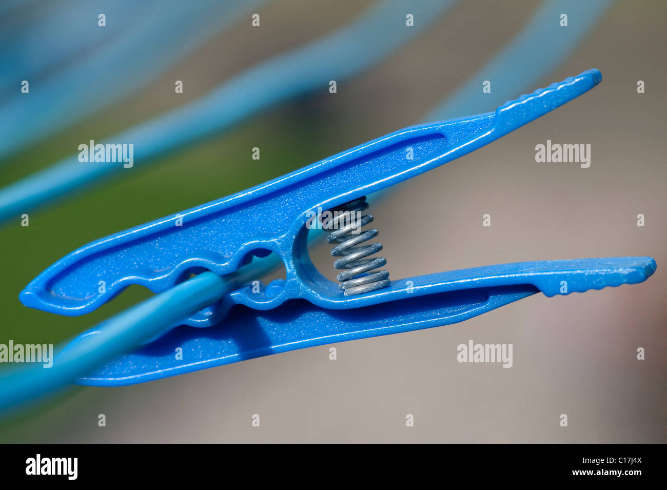 Close-up image of a plastic blue clothespeg hanging on a clothesline. Stock Photo