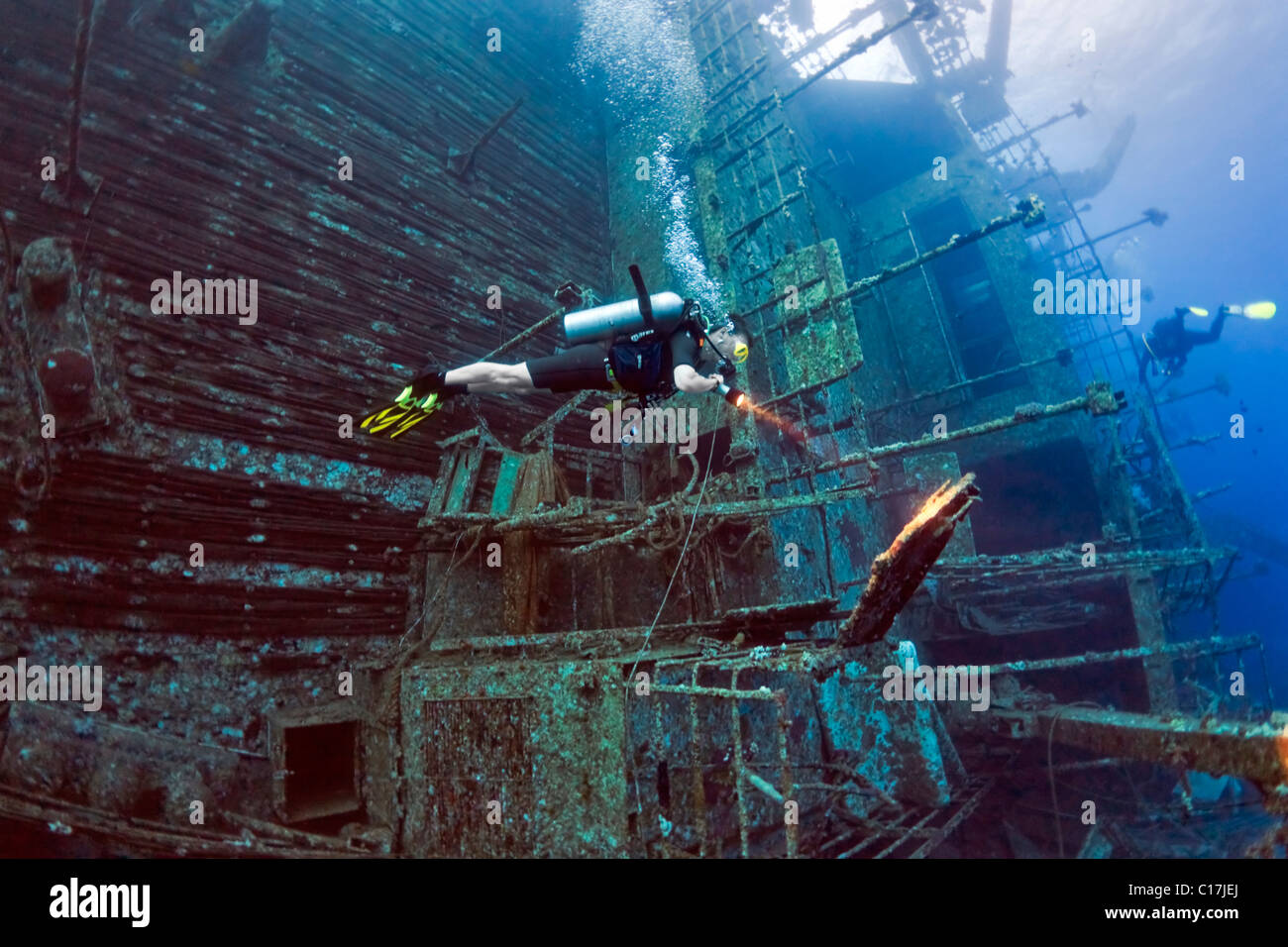 A scuba diver illuminates some wreckage on the deck of the sunken ferry shipwreck Salem Express on Hyndman Reef in the Red Sea. Stock Photo