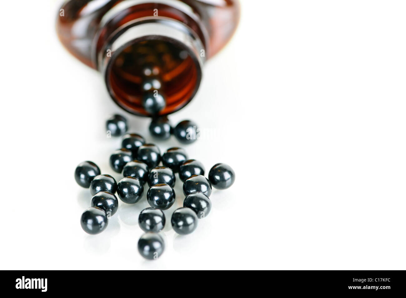 Traditional chinese herbal medicine pills spilling from bottle on white