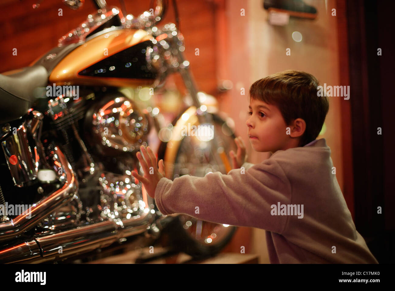 boy looks through shop window at motorcycles Stock Photo