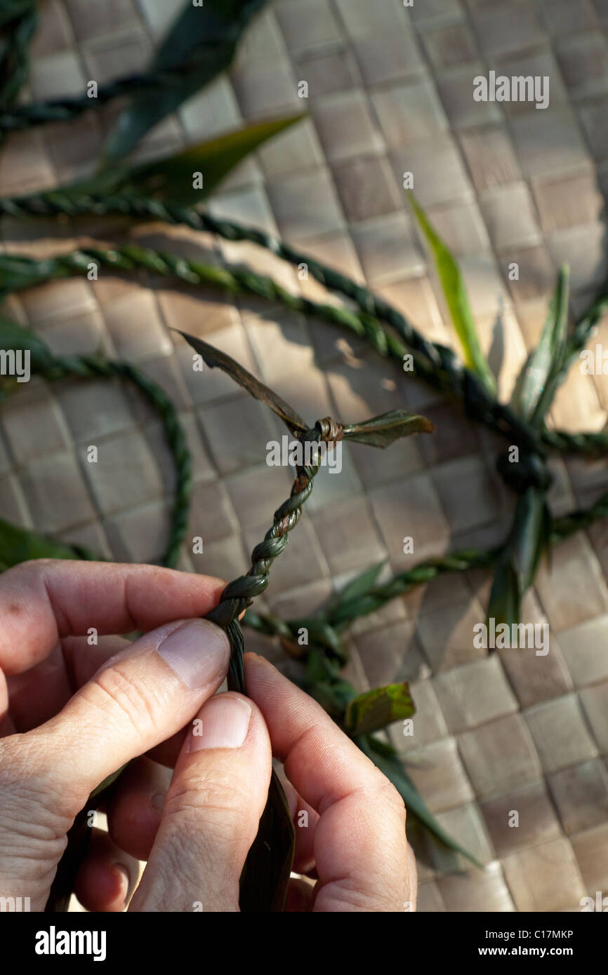 Traditional lei making with ti leaves in Hawaii. Stock Photo