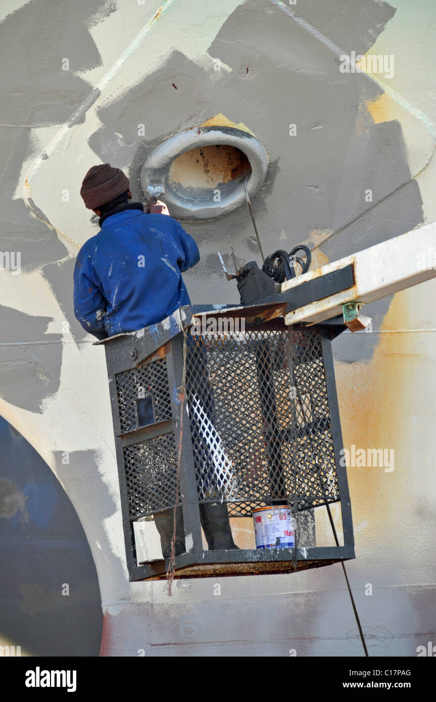 Varnisher applying anti-rust paint, renovation works on a drydock, Cape Town, South Africa Stock Photo