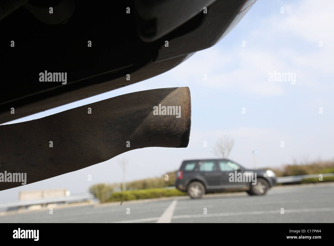 The exhaust pipe of a 4x4 vehicle can be seen with another car in the background March 8, 2011 in Wadebridge, United Kingdom. Stock Photo