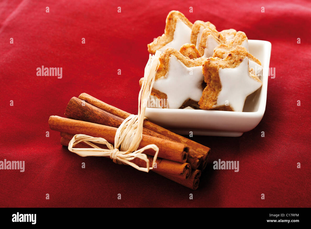 Cinnammon star-shaped biscuits and bundle of cinnammon sticks on red velvet Stock Photo