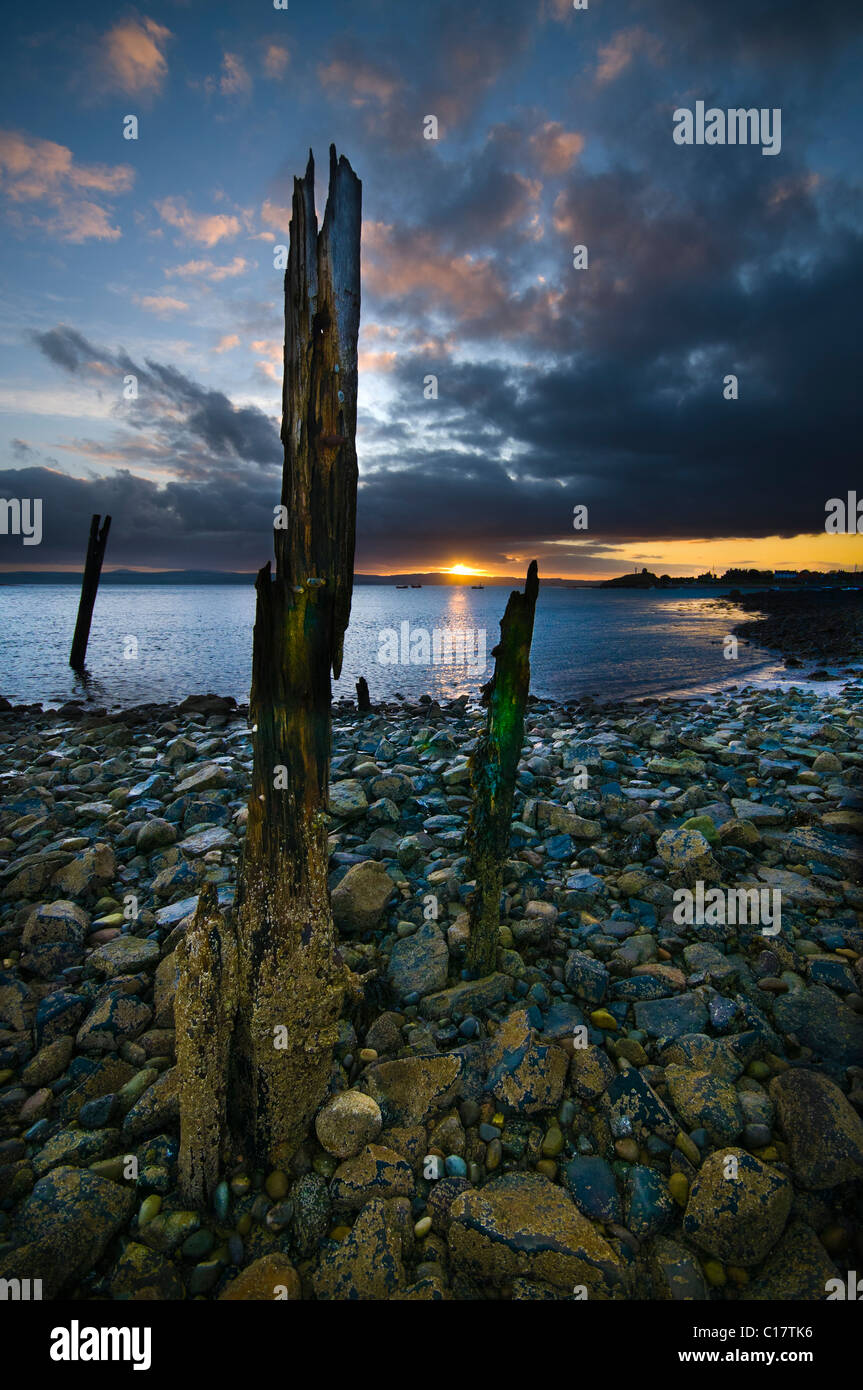 The remains of a pier on Holy Island looking towards the ruins of Lindisfarne Priory Stock Photo
