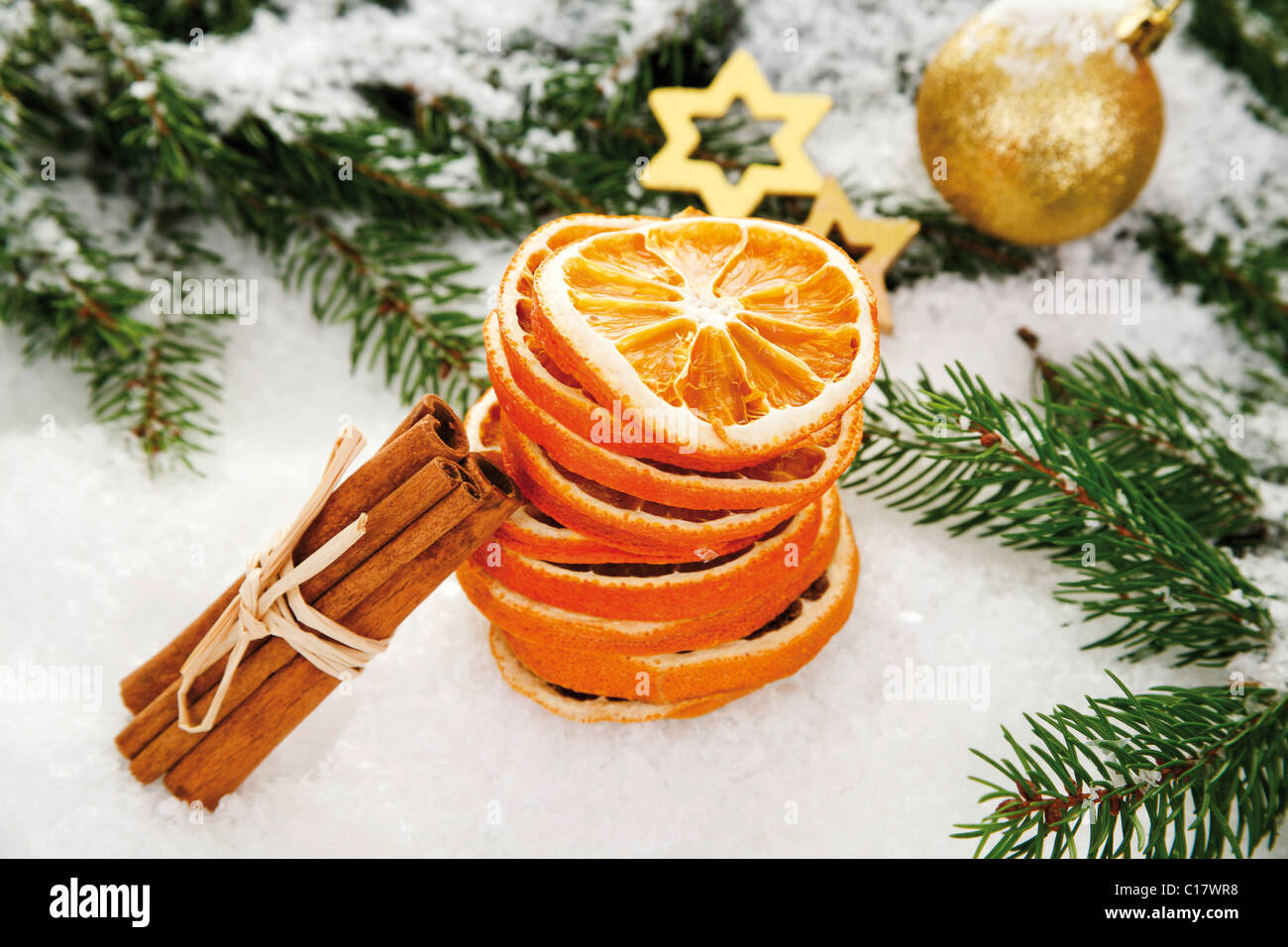 Dried orange slices with cinnamon sticks, a Christmas tree bauble, branches of fir and decorations on snow Stock Photo