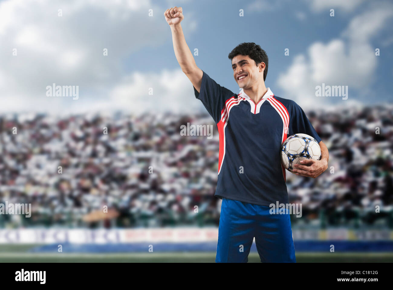 Soccer player holding a soccer ball and clenching fist Stock Photo