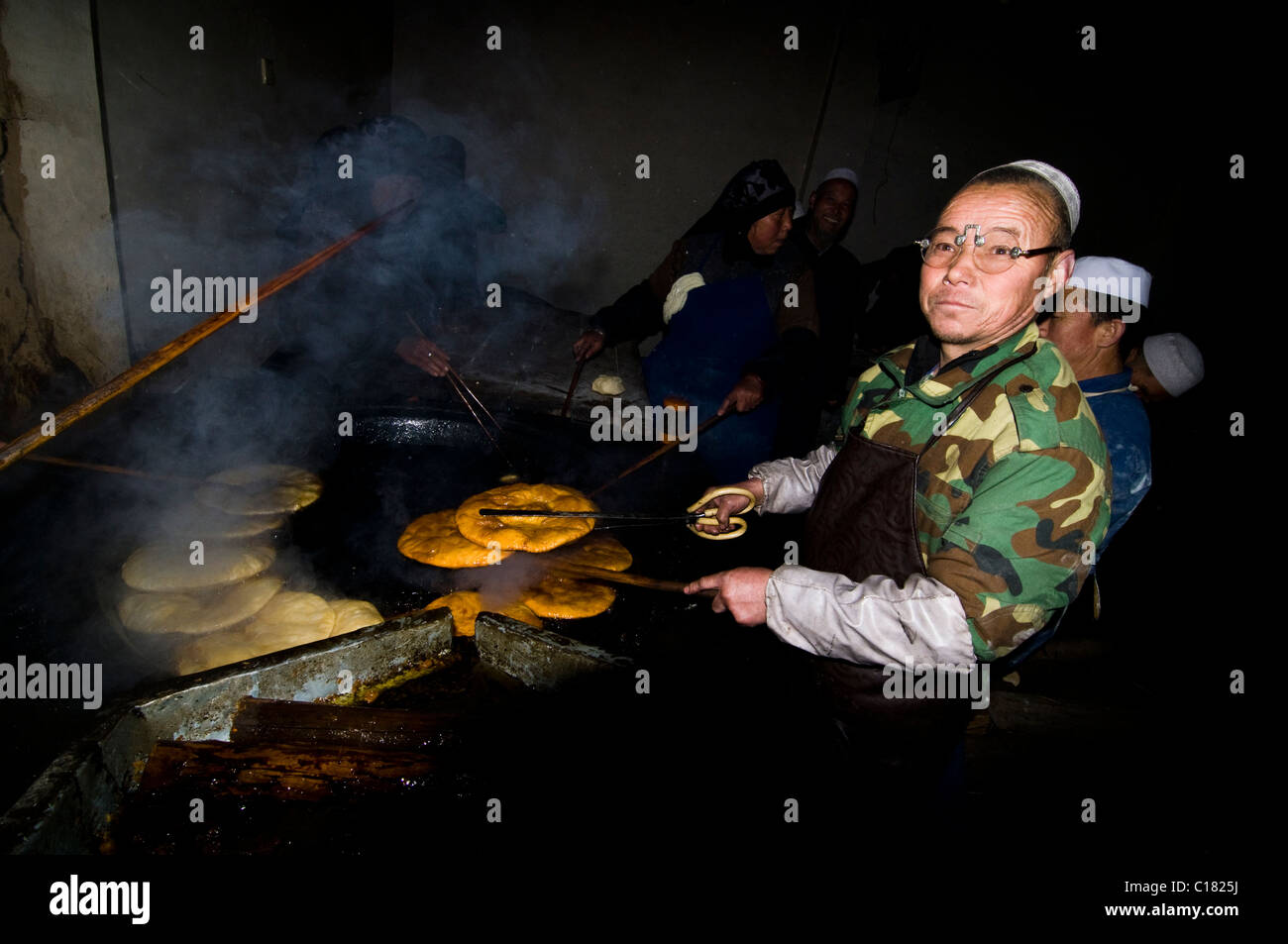 Hui Muslims makling a traditional flat bread in a small bakery in the old city of Linxia, Gansu. Stock Photo
