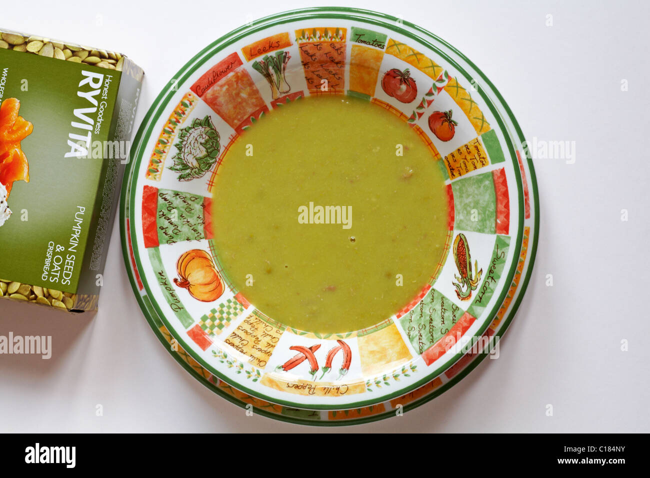 Bowl of pea and ham soup with packet of Ryvita pumpkin seeds and oats crispbread set on white background Stock Photo