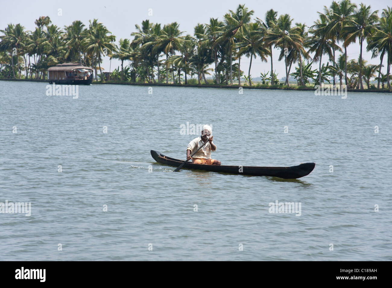 Man paddling on a canoe with palm trees at the background Stock Photo