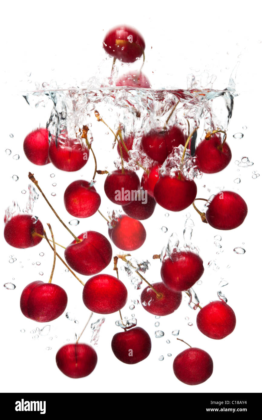 Photo of red cherries falling into water with a white background.Motion blur. Stock Photo