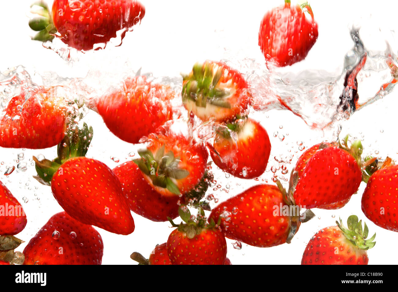 Photo of strawberries falling into water against a white background.Motion blur. Stock Photo