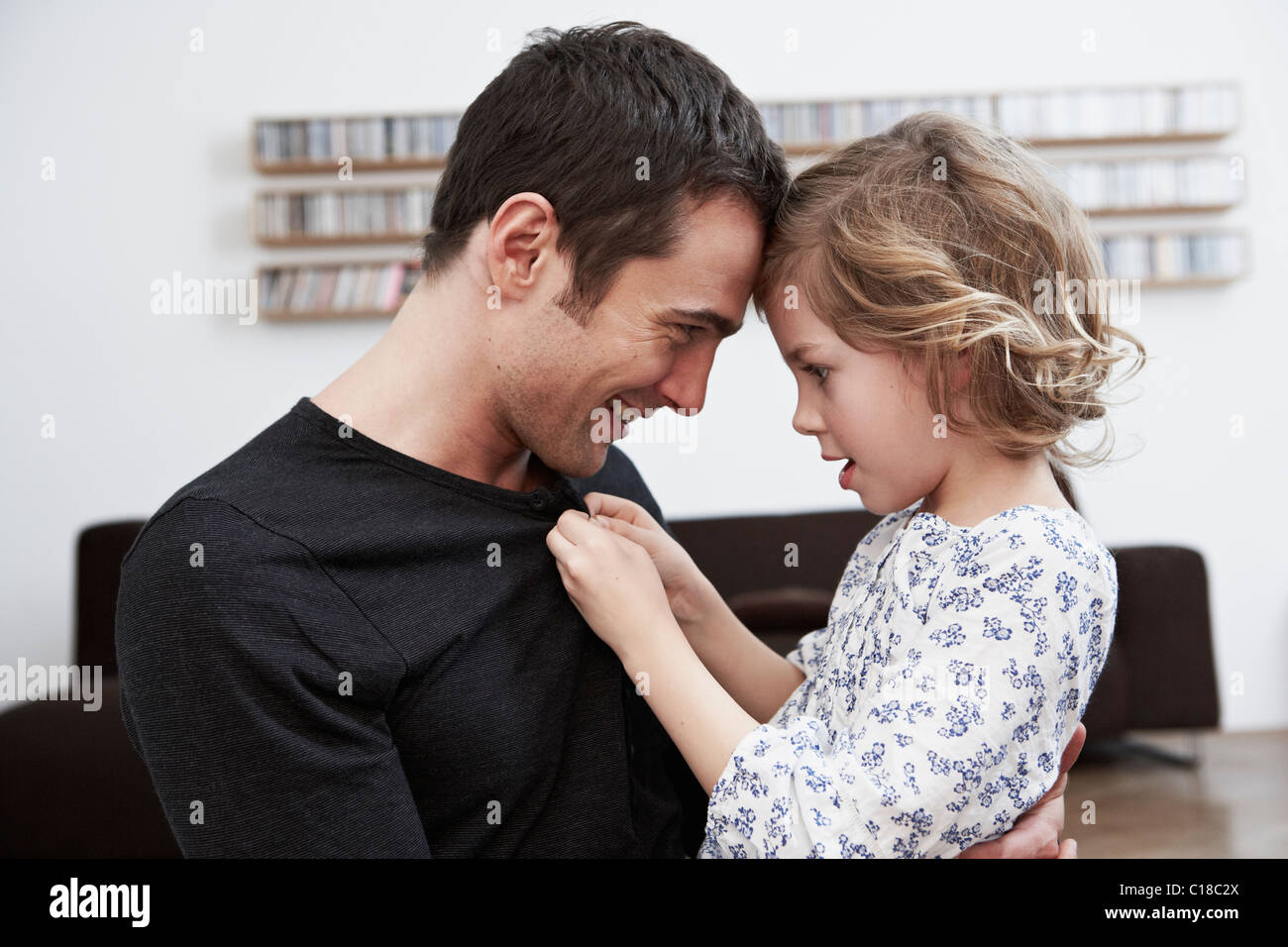 Girl buttoning up fathers shirt Stock Photo