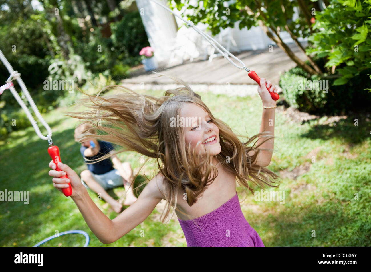 Girl jumping rope in garden Stock Photo Alamy