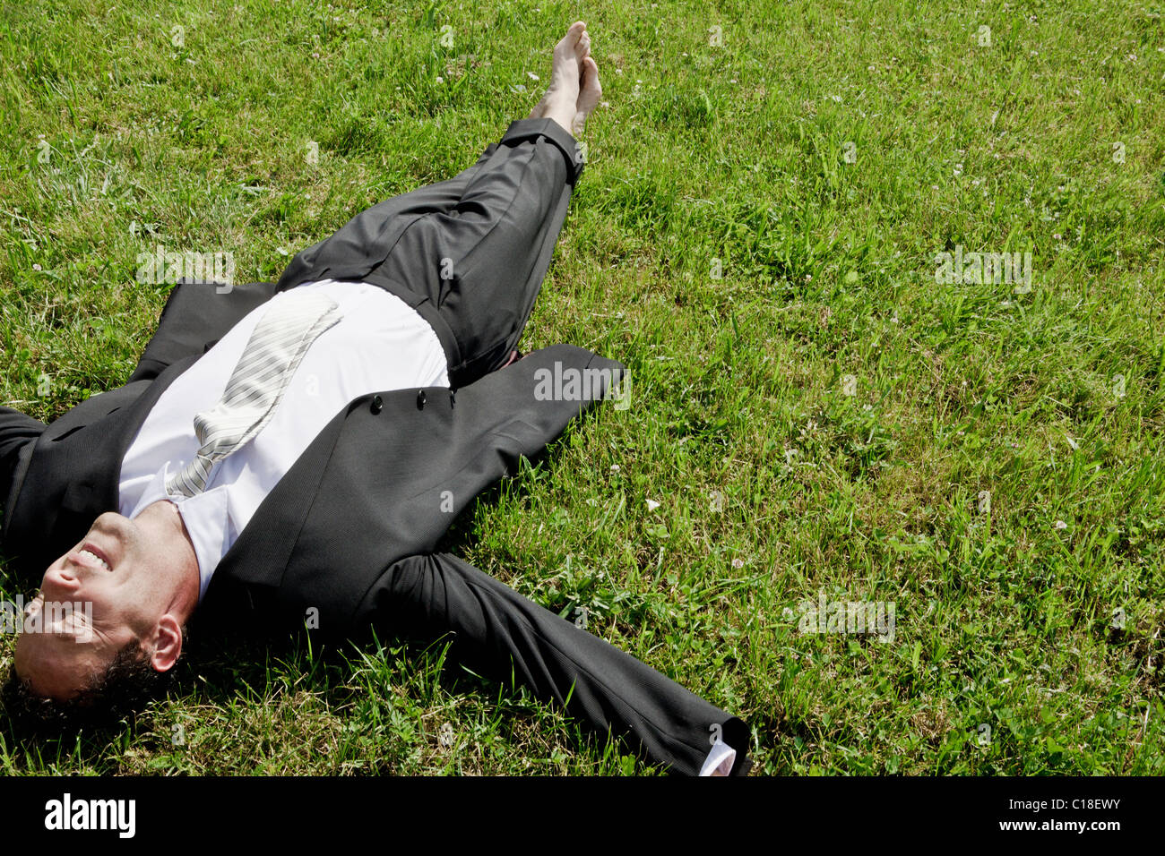Barefoot businessman lying on grass Stock Photo