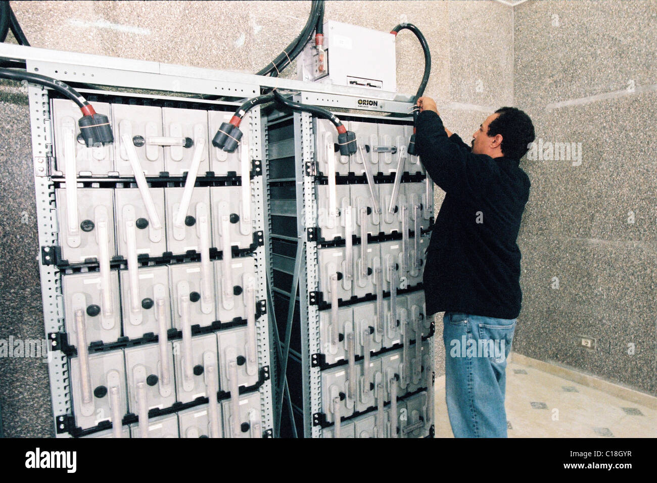 A IT technician doing routine battery backup storage maintenance in a ...