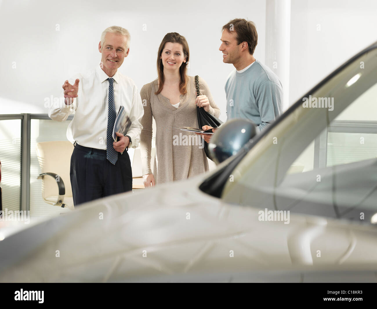 Salesman and customers in car dealership Stock Photo Alamy
