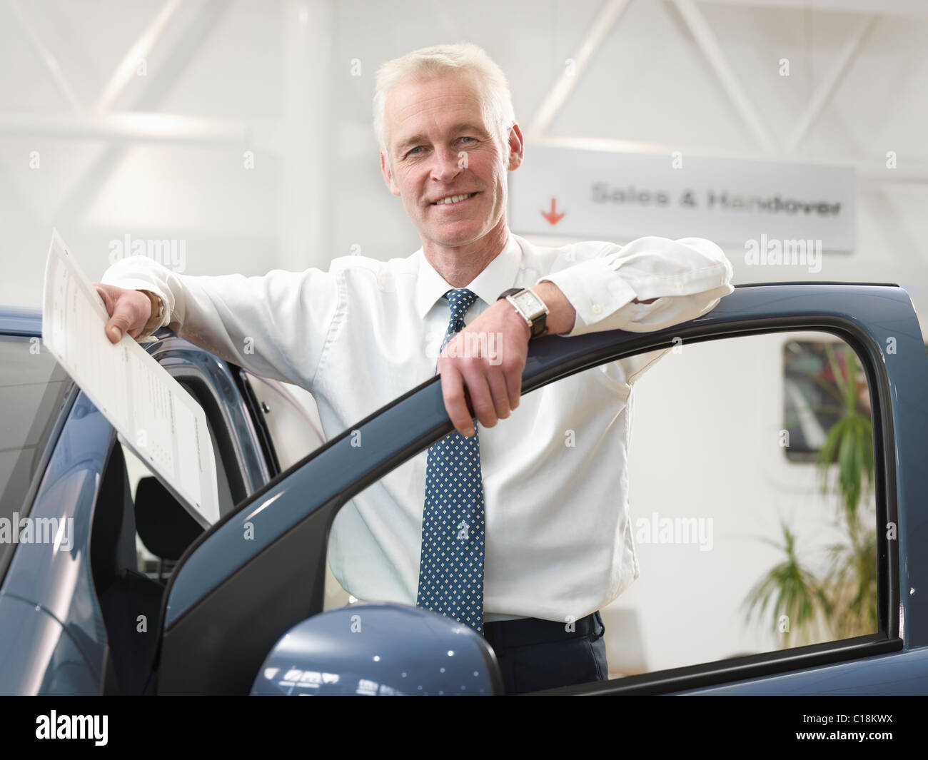 Salesman with car in car dealership Stock Photo