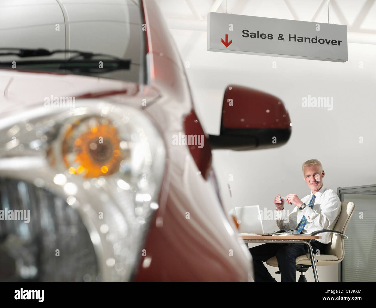 Salesman at desk in car dealership Stock Photo Alamy