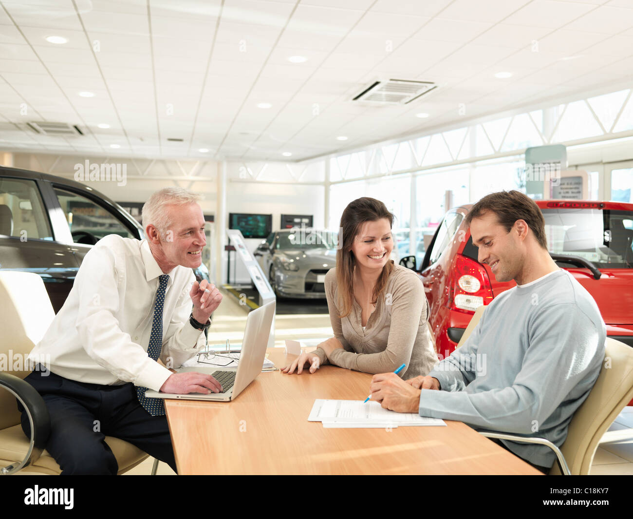 Salesman and customers in car dealership Stock Photo