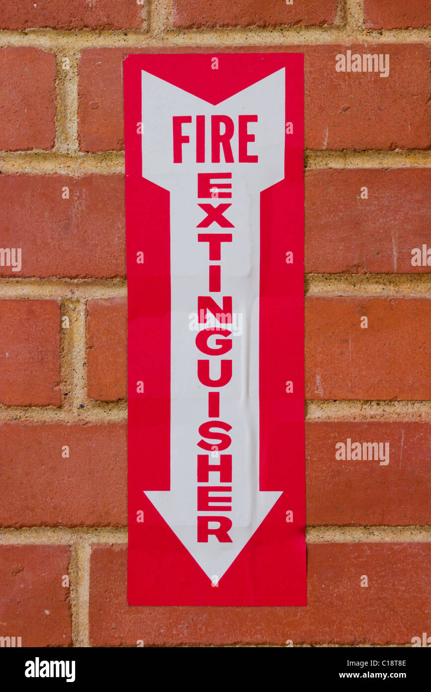 Sign pointing downward to location of a fire extinguisher on a red brick wall Stock Photo Alamy