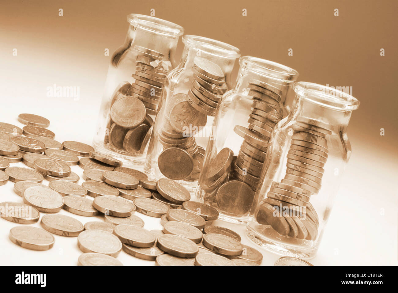 Glass jars full of coins, excess coins aside Stock Photo