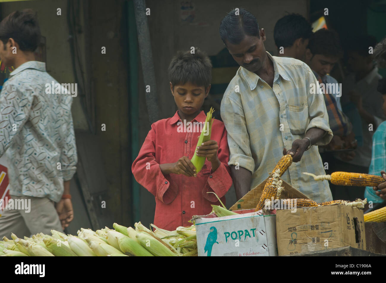 A man teaching a boy how to sell corn in India Stock Photo Alamy