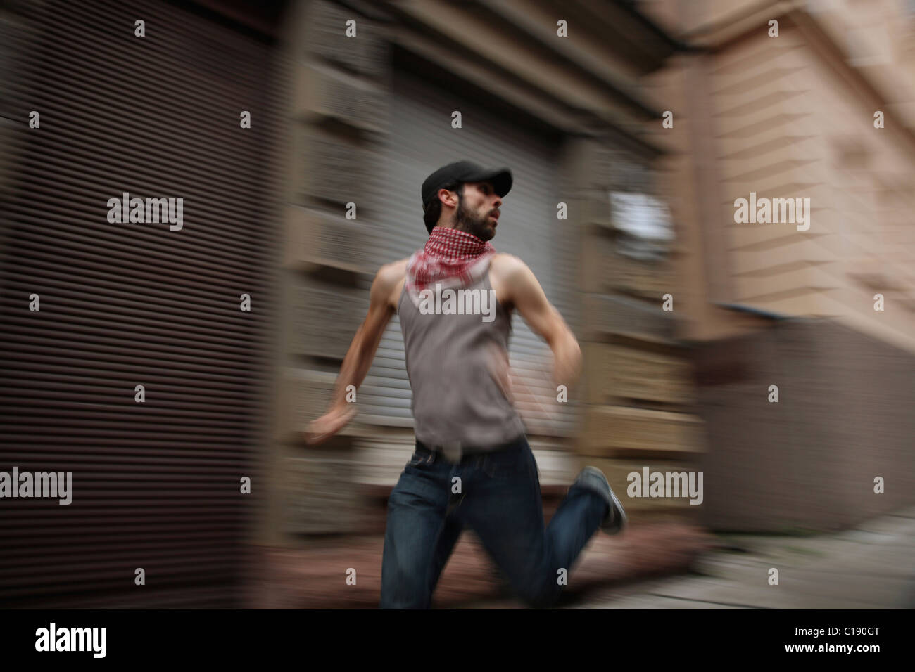 Man wearing Palastinian scarf running through the city streets, looking