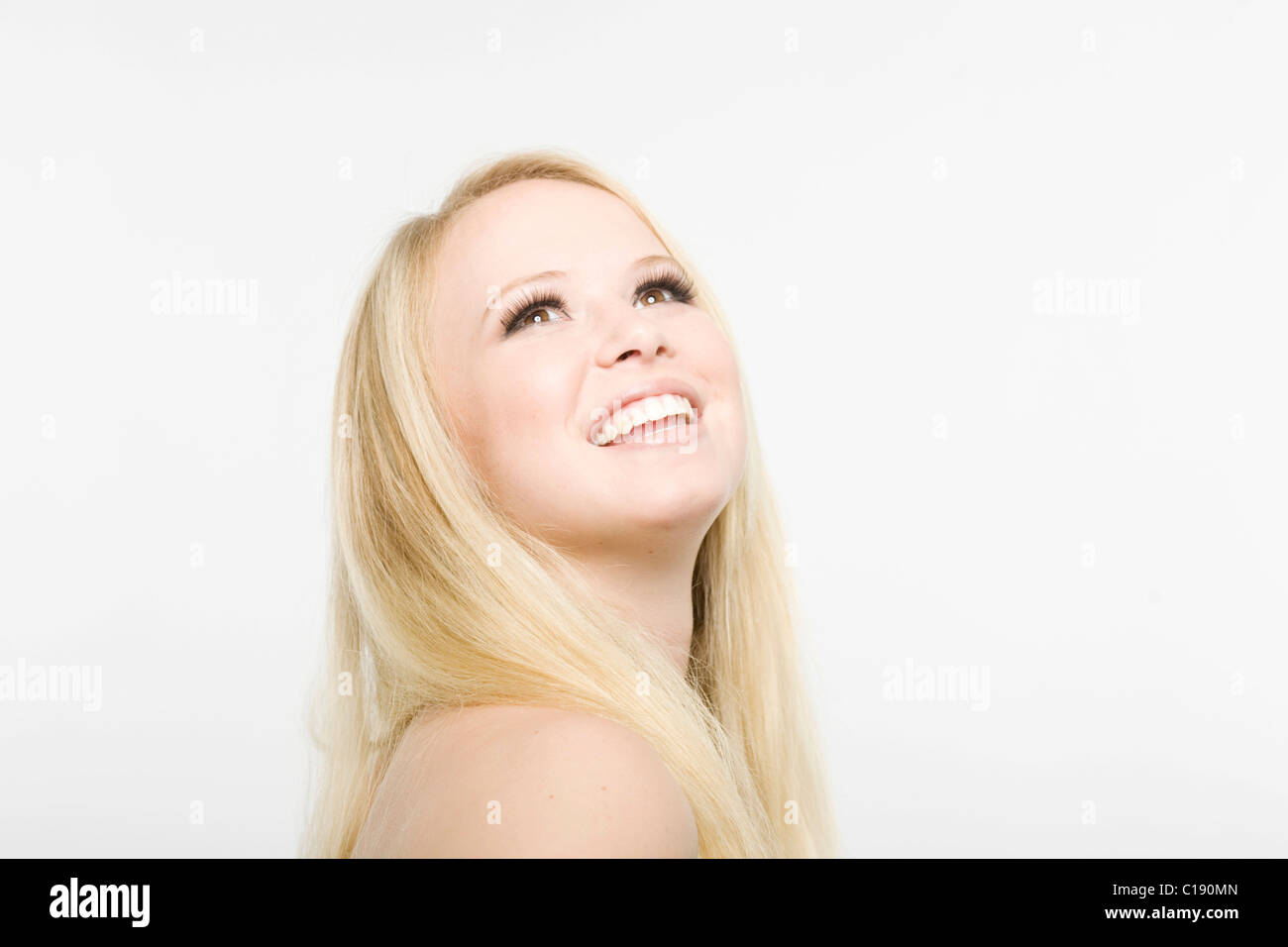 Young blonde woman looking up, smiling Stock Photo