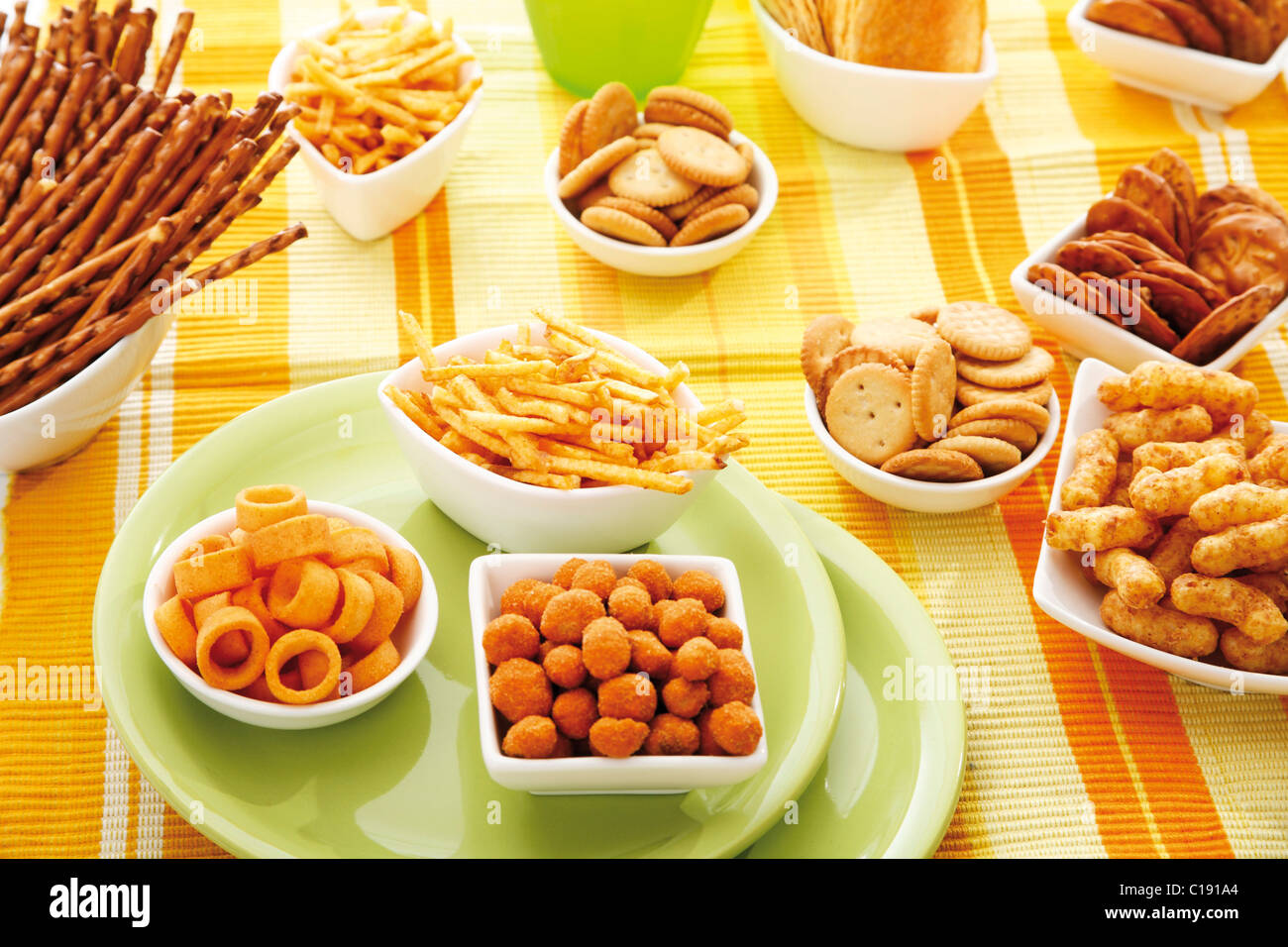 Various spiced snacks in bowls, crisps, peanut flips, potato sticks, roasted peanuts, pretzel sticks and potato rings Stock Photo
