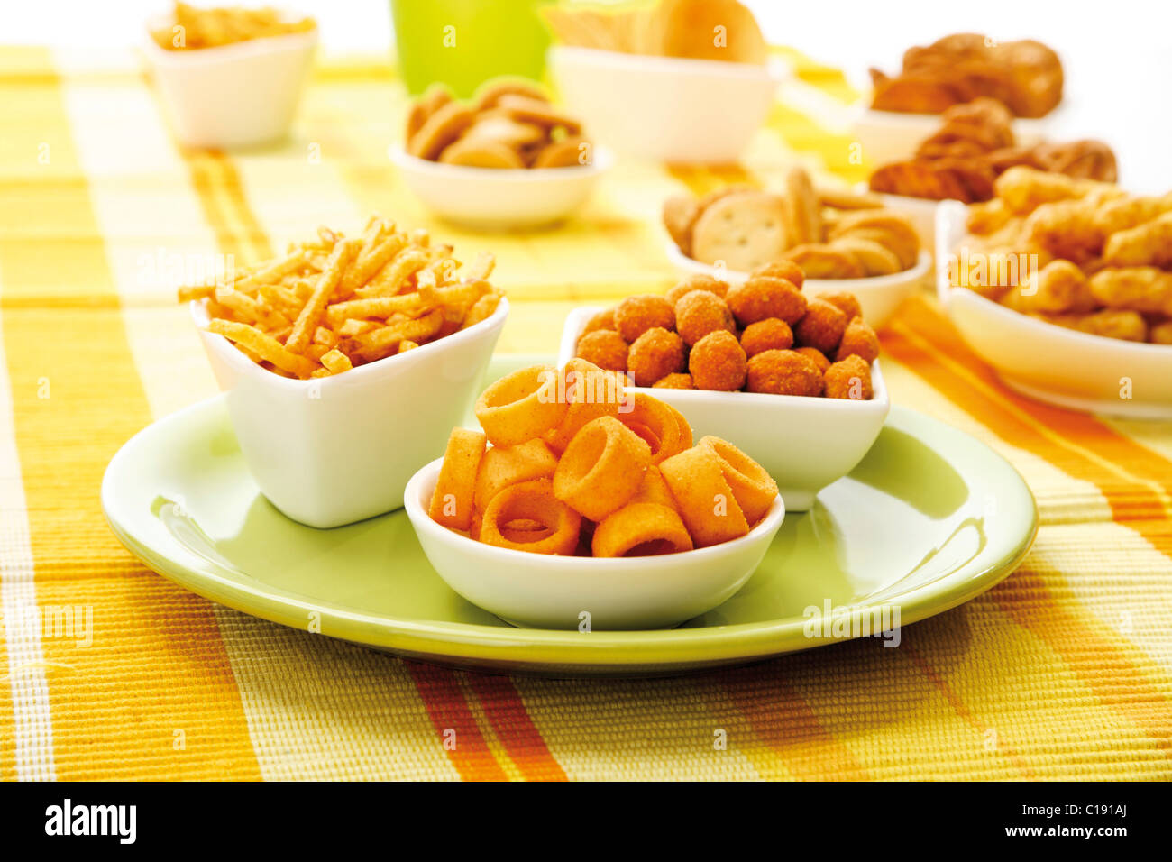 Various spiced snacks in bowls, crisps, peanut flips, potato sticks, roasted peanuts and potato rings Stock Photo