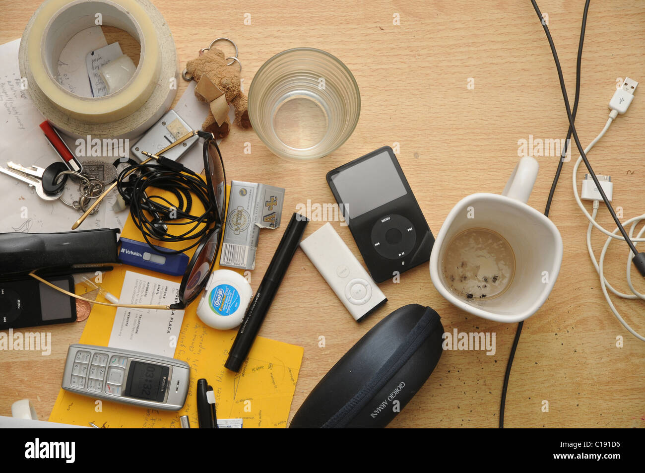 A perpendicular view of a messy desk surface with all sorts of stationary, electronics and dirty mugs. Stock Photo