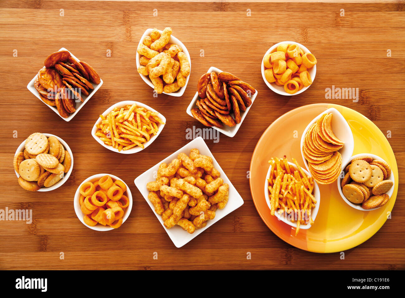 Various spiced snacks in bowls on a table, crisps, peanut flips, potato sticks, roasted peanuts, pretzel sticks and potato rings Stock Photo