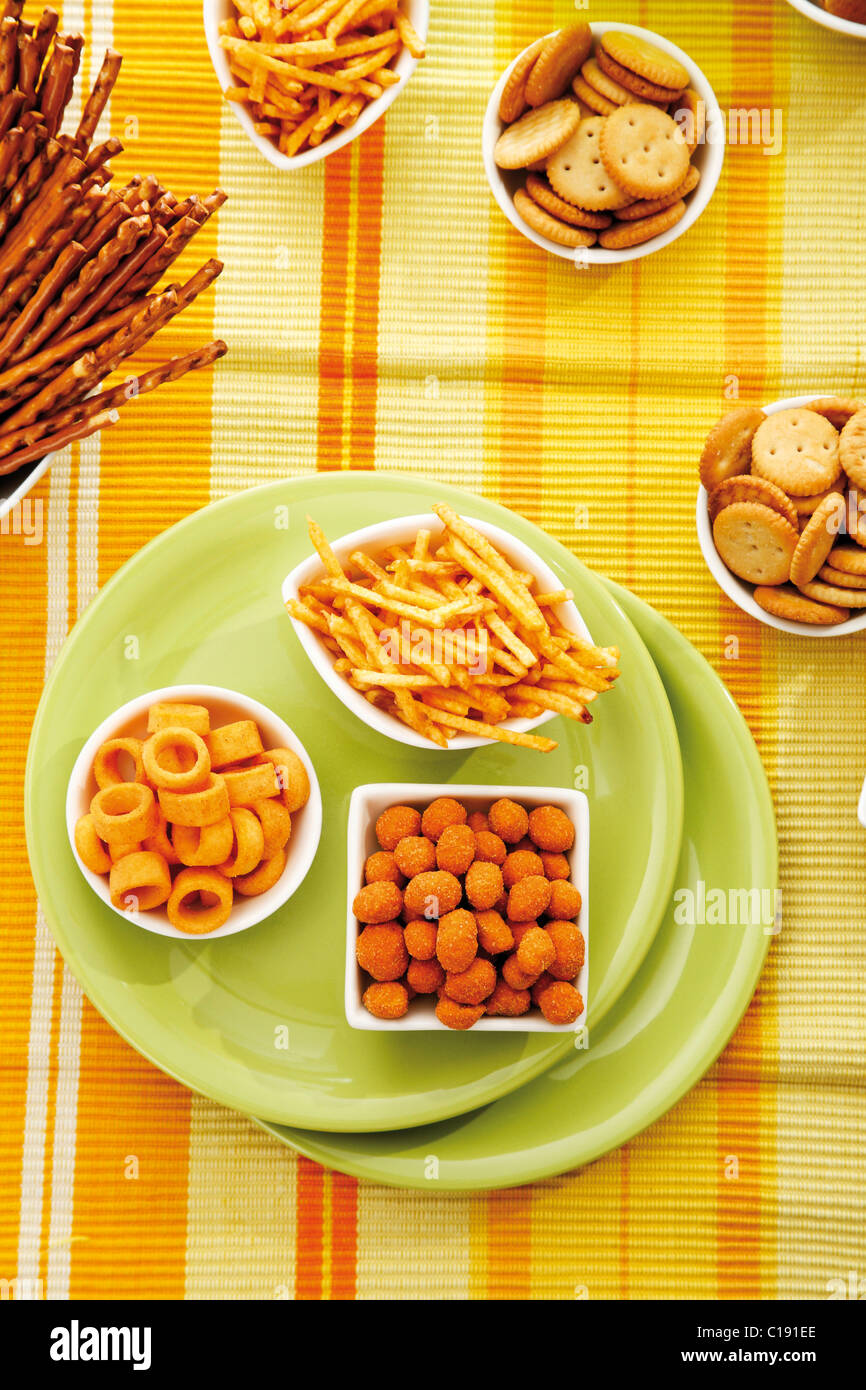 Various spiced snacks in bowls, crisps, potato sticks, roasted peanuts