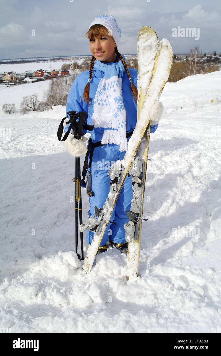 The young girl in sportswear costs and holds mountain skiing, a