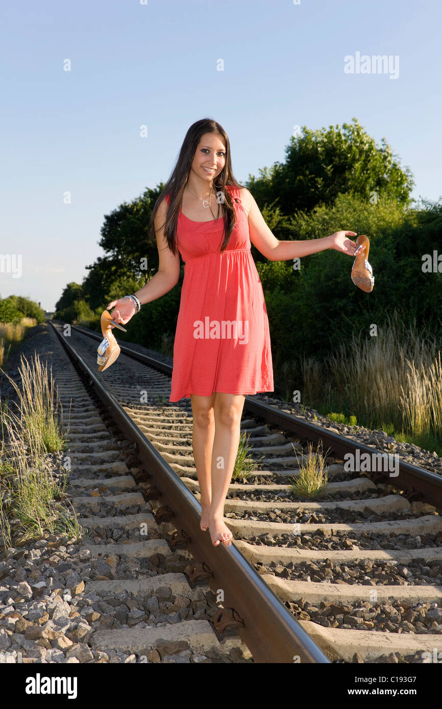Young woman, nineteen years old, balancing barefoot on a rail Stock