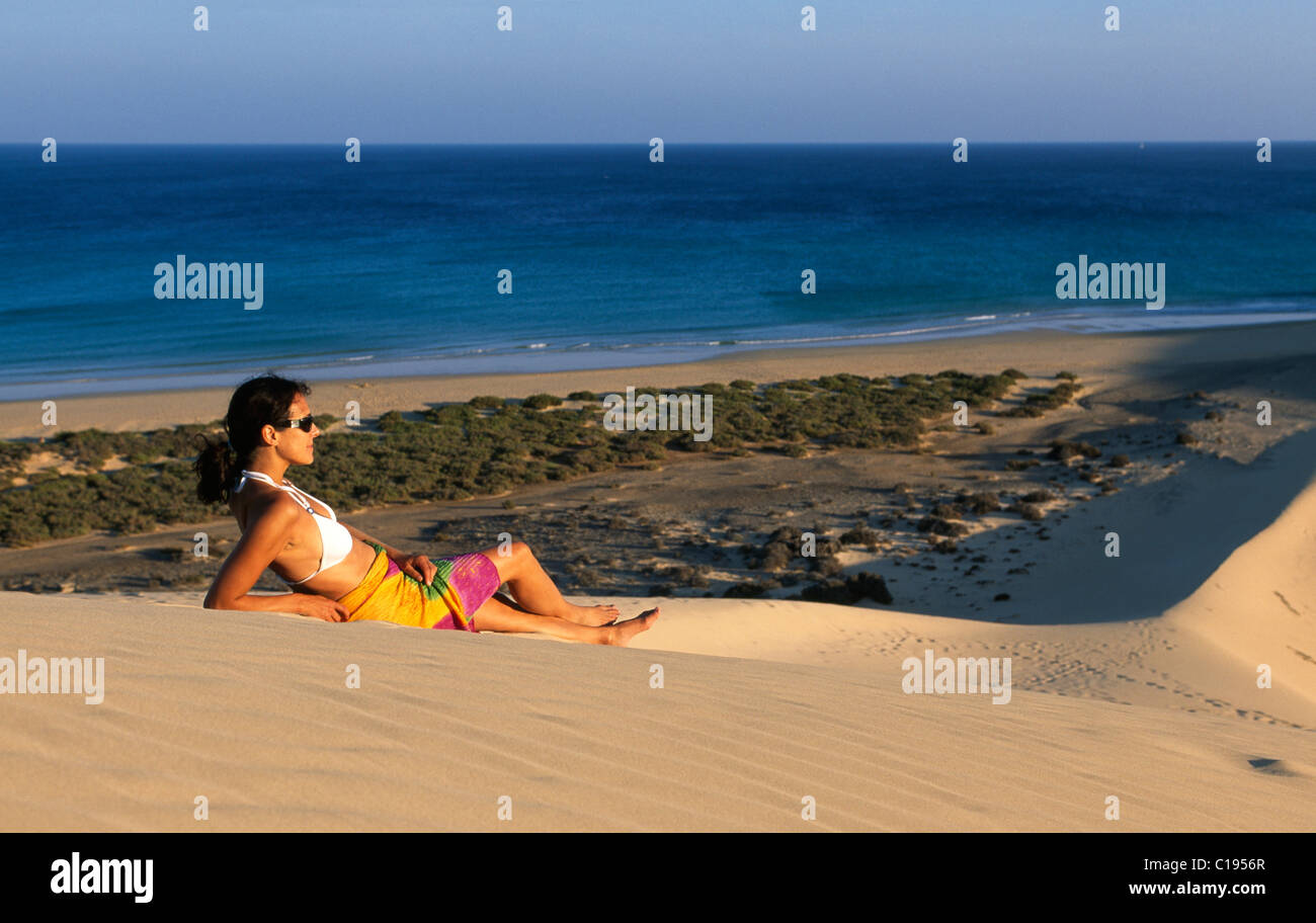 Woman lying on a sand dune overlooking the Playas de Sotavento beach, Fuerteventura, Canary Islands, Spain, Europe Stock Photo