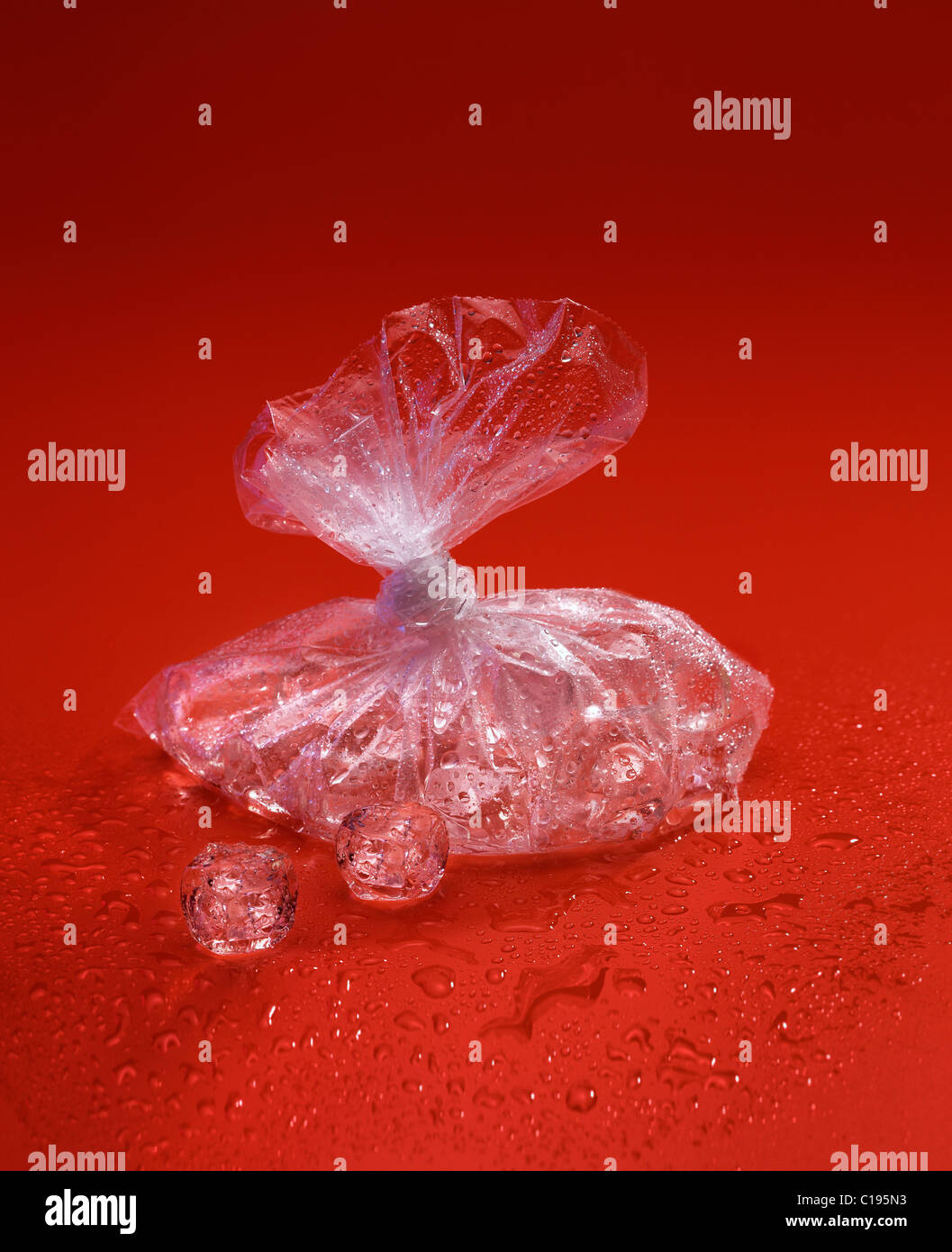 Translucent plastic bag with ice cubes on a red surface Stock Photo