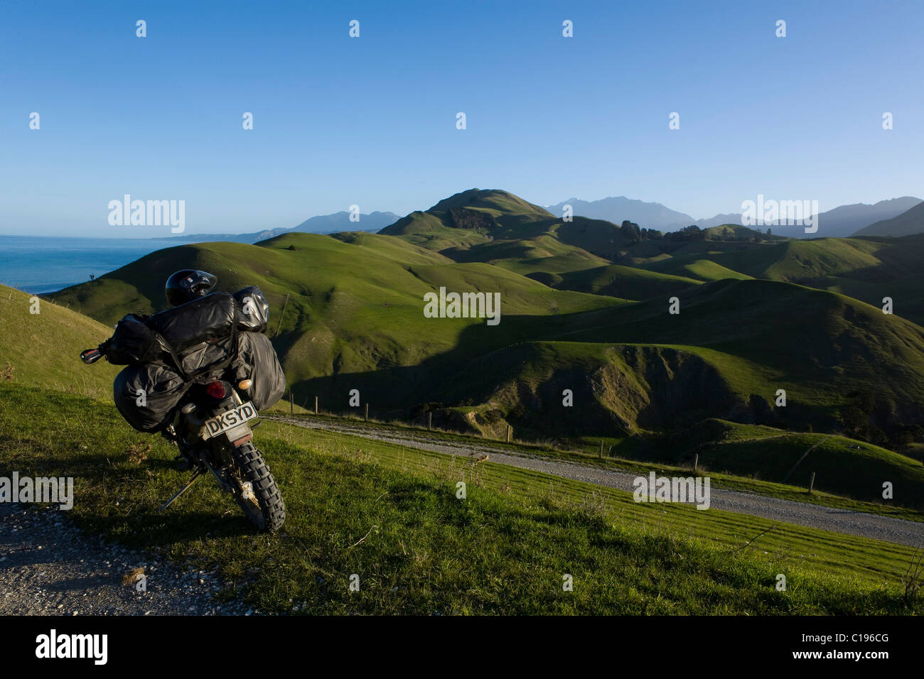 Heavily laden enduro motorbike in a green hilly landscape, Kaikoura Range, South Island, New Zealand Stock Photo