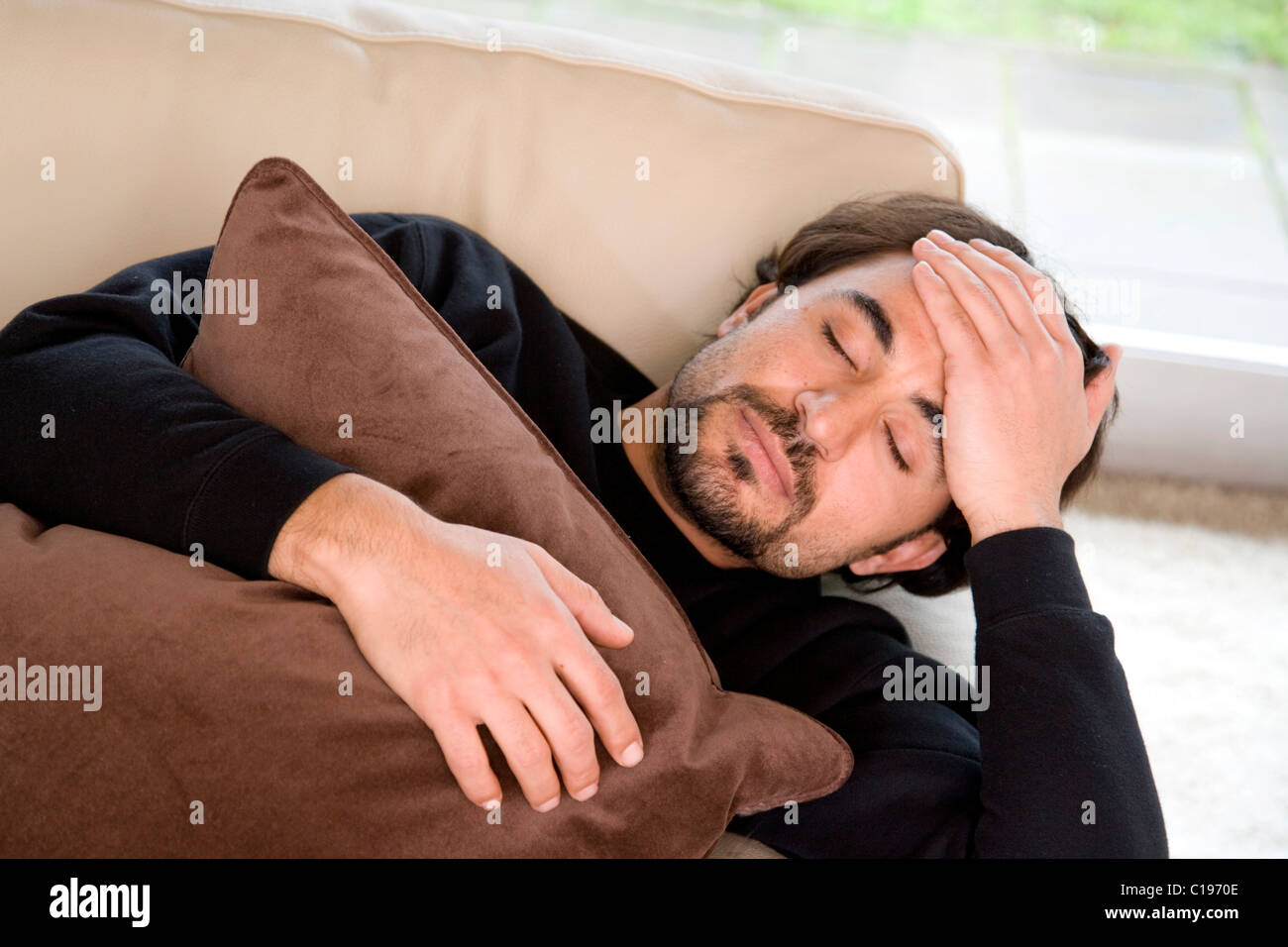 Man with a headache sleeping on a sofa Stock Photo Alamy