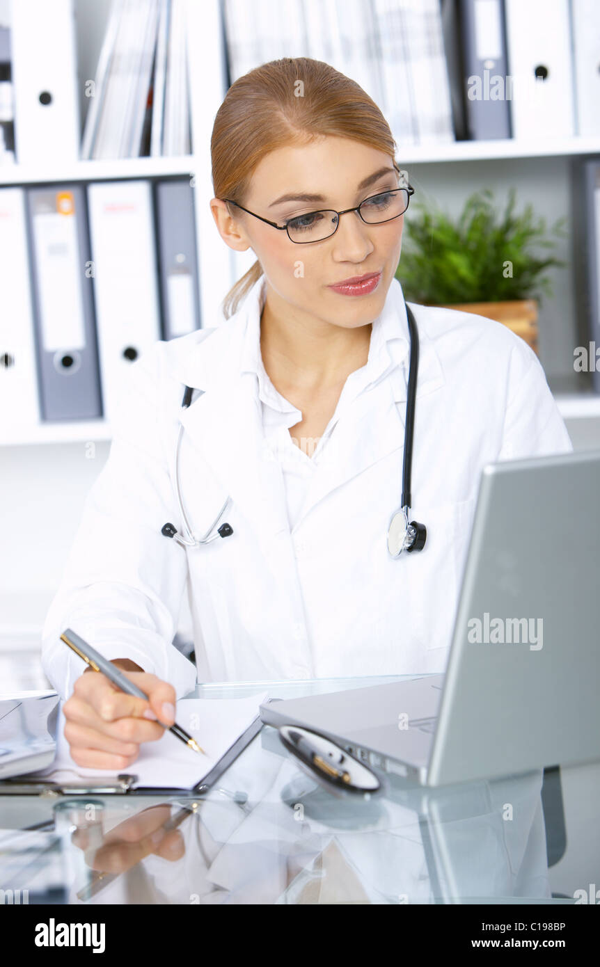Smiling female doctor writing notes in clipboard Stock Photo - Alamy