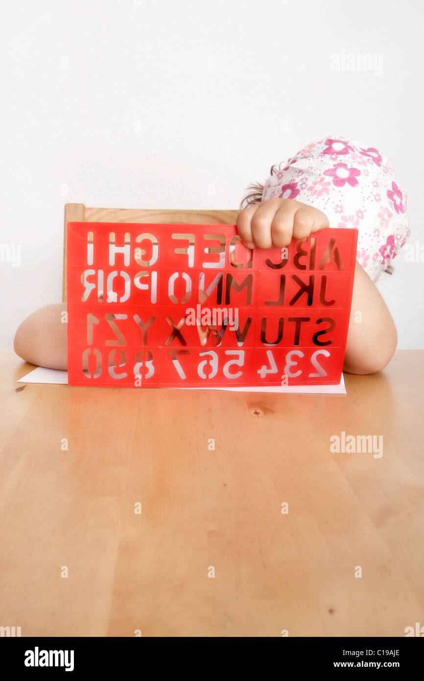 6 Year Old Girl Sitting At A Desk Behind An Alphabet Stencil Stock