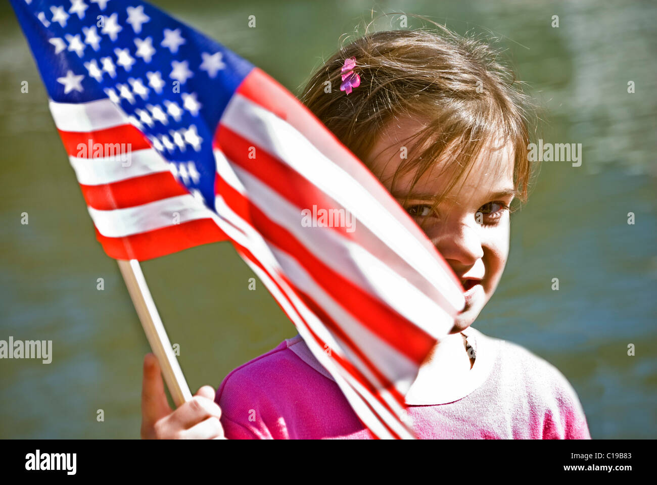 A cute girl smiling and holding onto her flag that's flying in the wind. Stock Photo