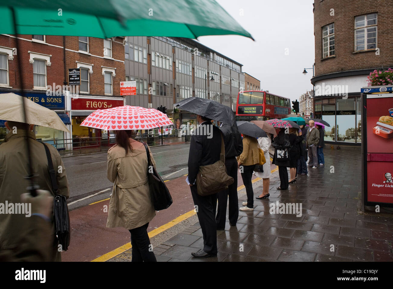 People queue in the rain for a bus on a wet Tuesday morning at the ...