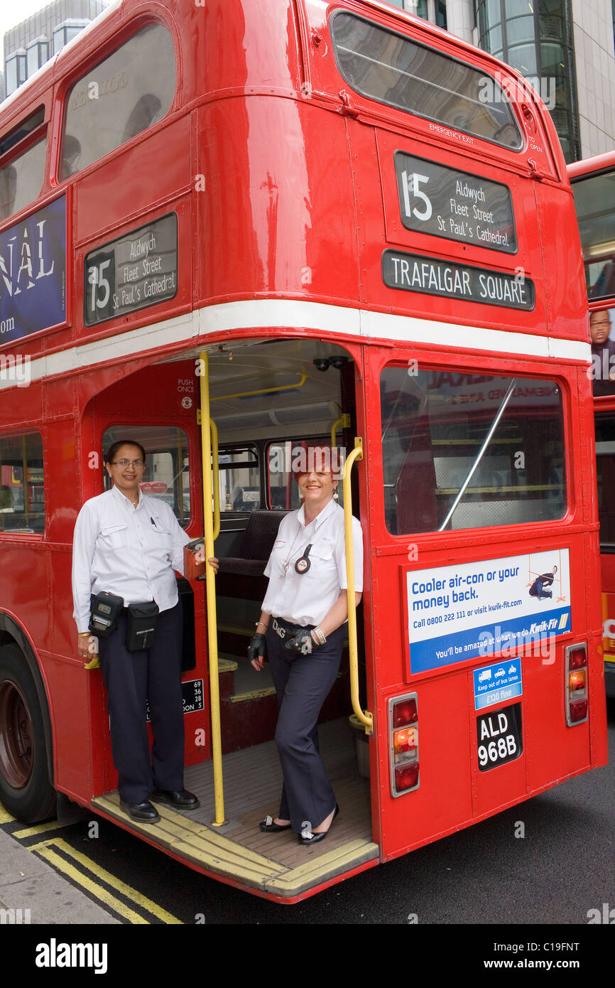 A female conductor and driver pose for a photograph on the back of the red London Routemaster bu number 15 on which they are wor Stock Photo